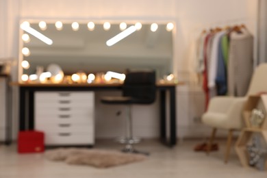 Photo of Blurred view of makeup room with stylish mirror, dressing table and chair