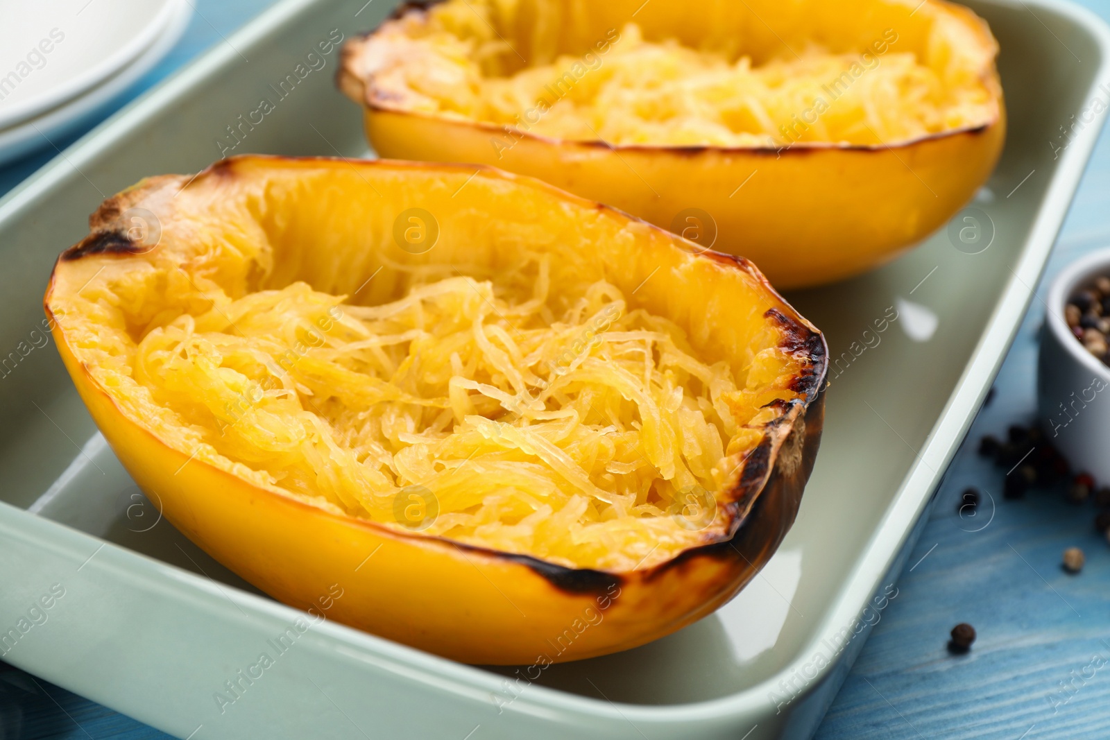 Photo of Halves of cooked spaghetti squash in baking dish on table, closeup