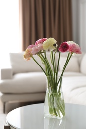Photo of Beautiful ranunculus flowers on table in living room