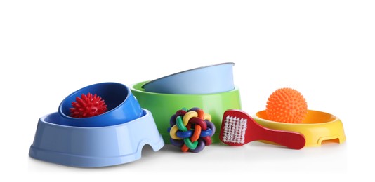 Feeding bowls, brush and dog toys on white background