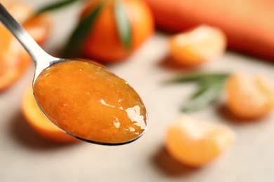 Spoon with delicious tangerine jam, closeup. Space for text