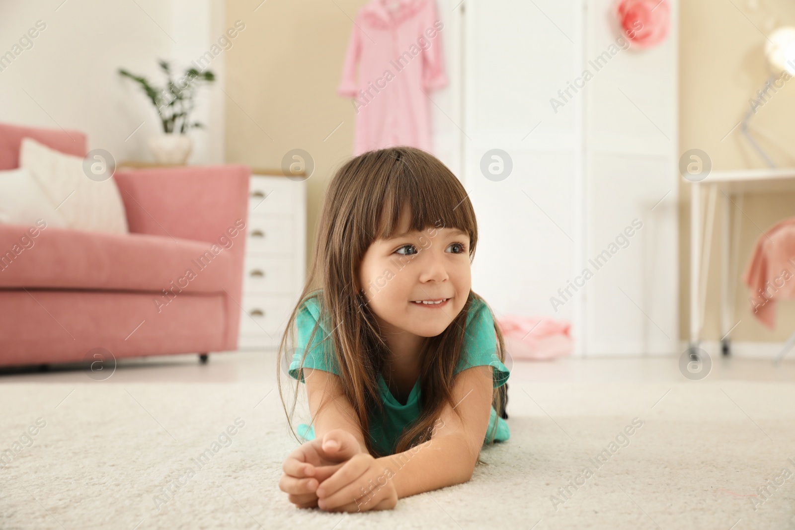 Photo of Cute little girl lying on carpet at home