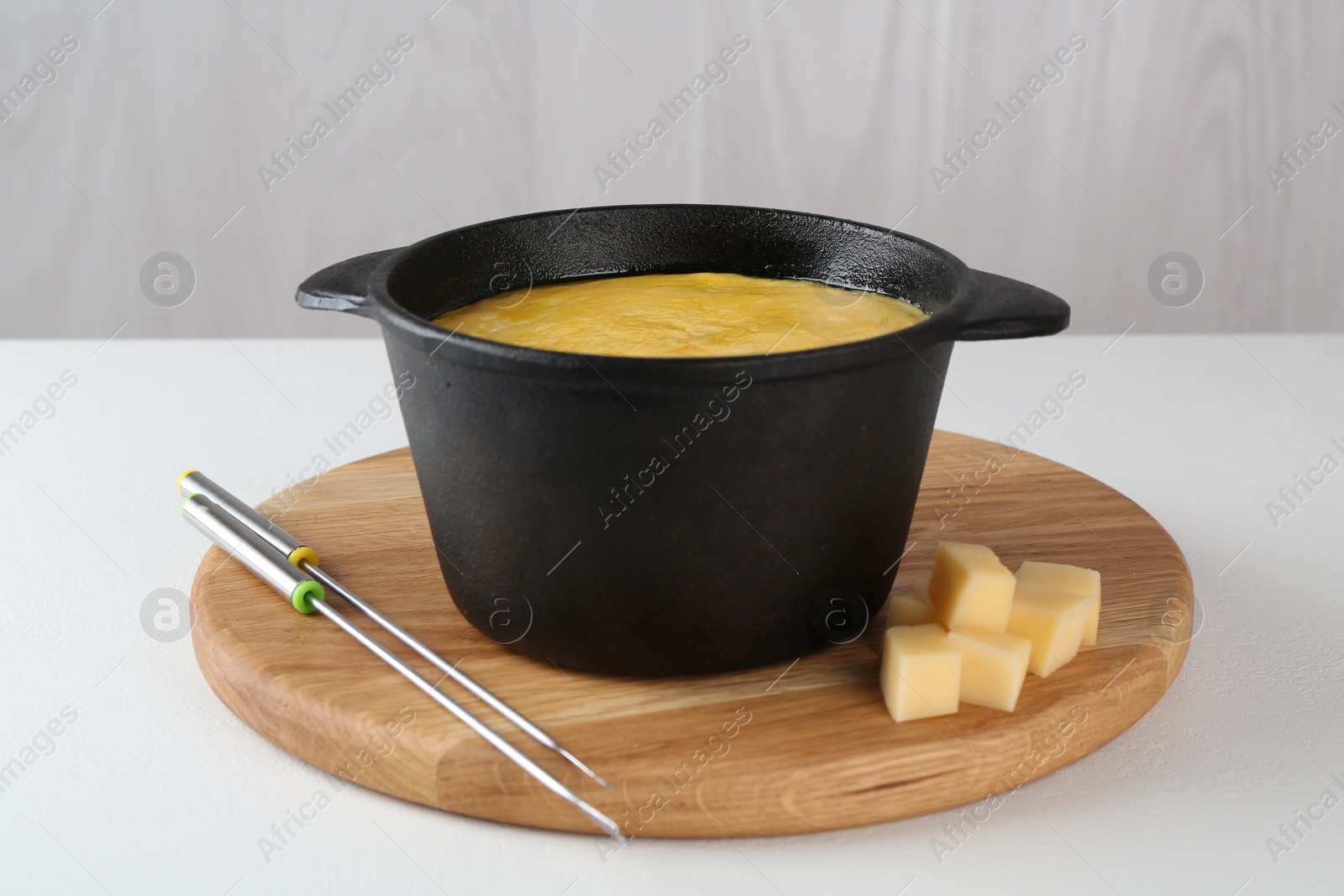 Photo of Fondue with tasty melted cheese and forks on white table