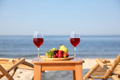 Photo of Glasses with wine and fruits on table at resort