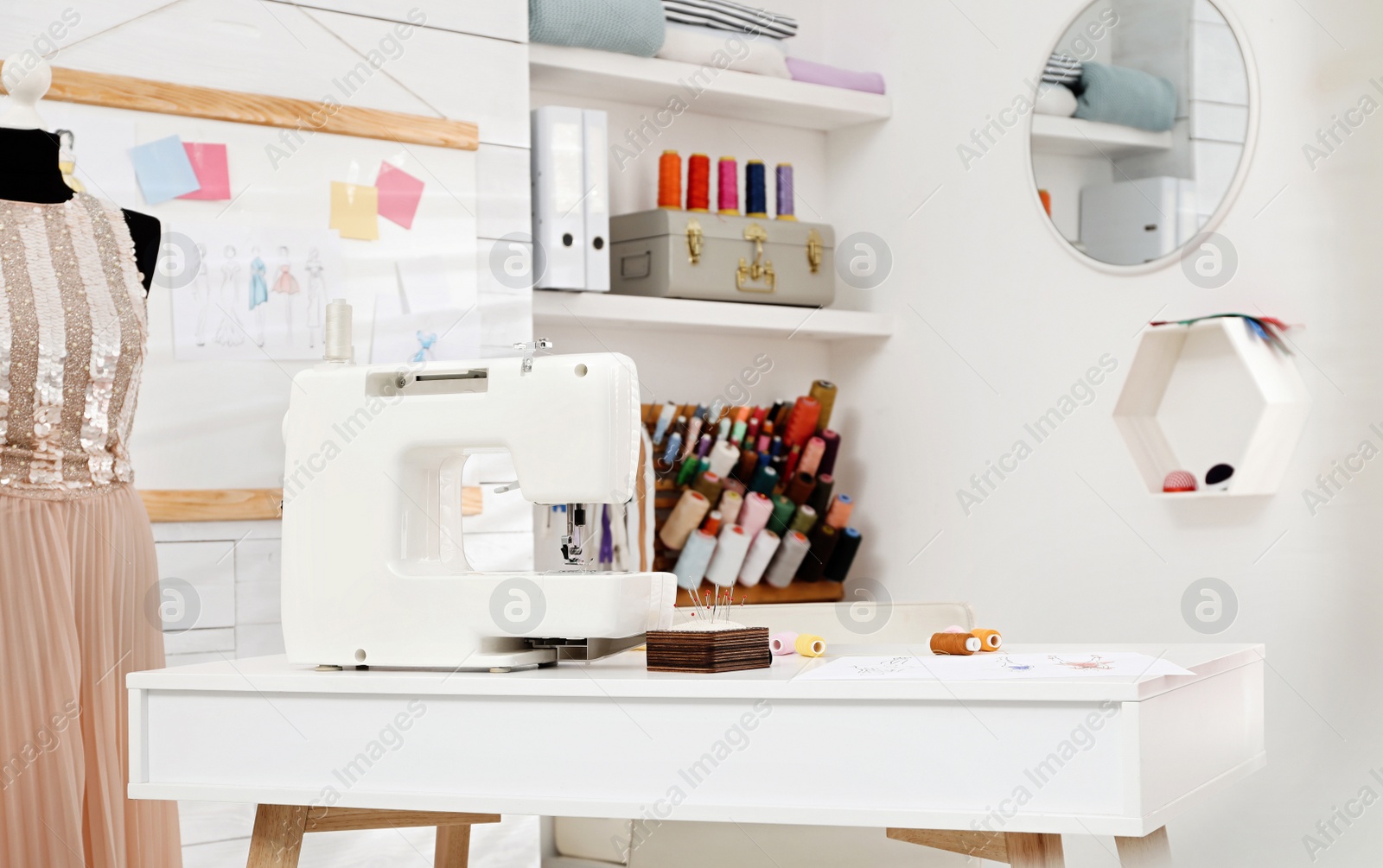 Photo of Dressmaking workshop interior with modern sewing machine, mannequin and accessories