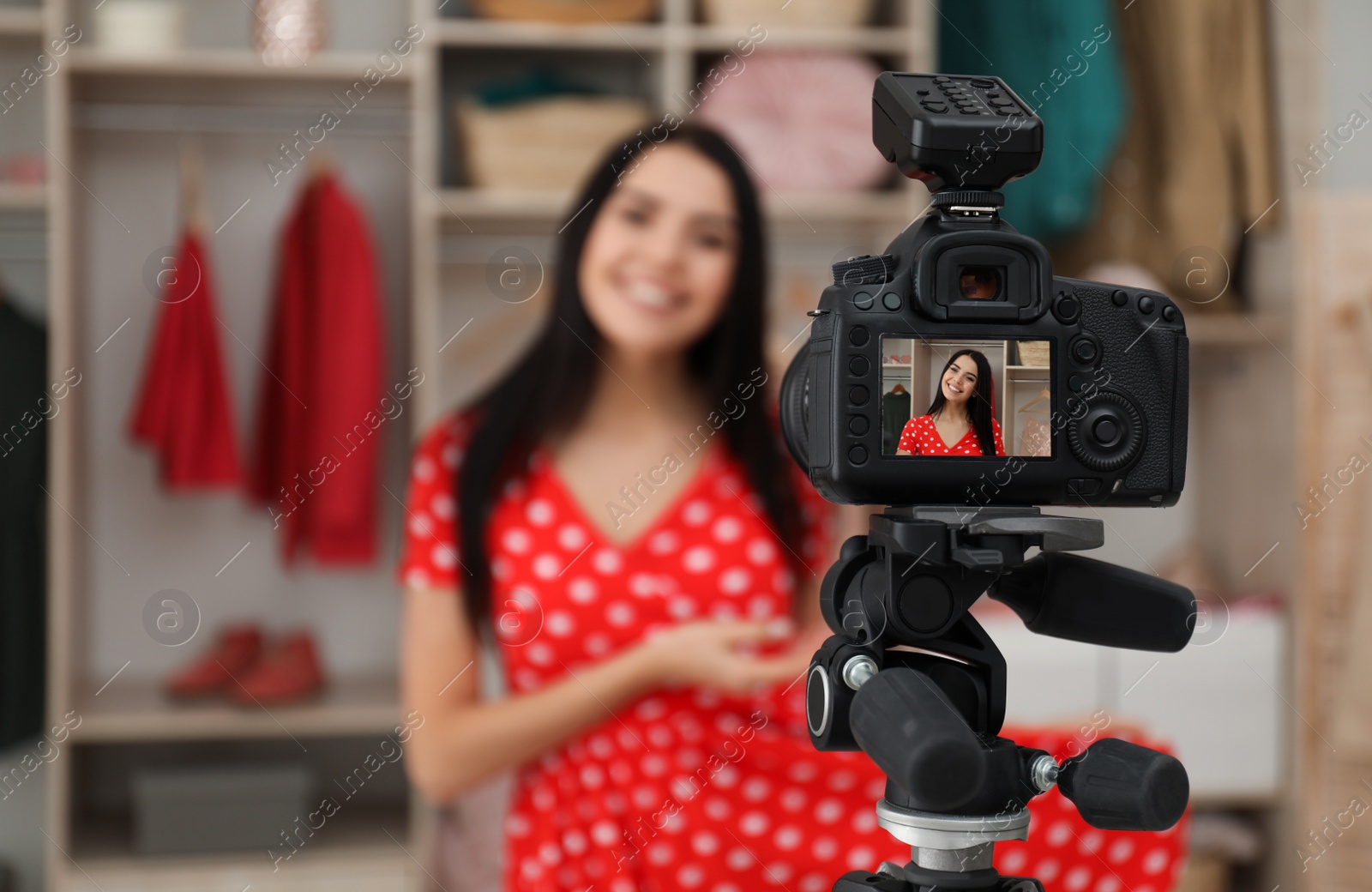 Photo of Fashion blogger recording new video in room, focus on camera