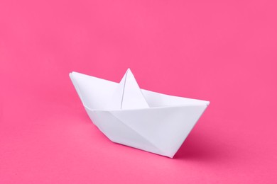 Photo of White paper boat on pink background. Origami art