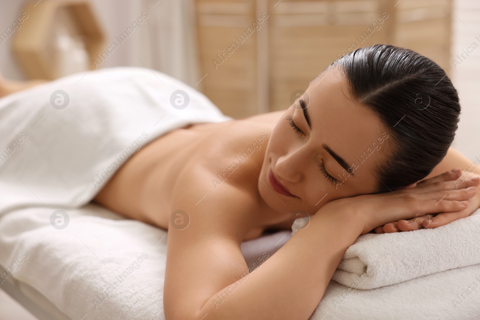 Photo of Beautiful woman relaxing on massage couch in spa salon, space for text