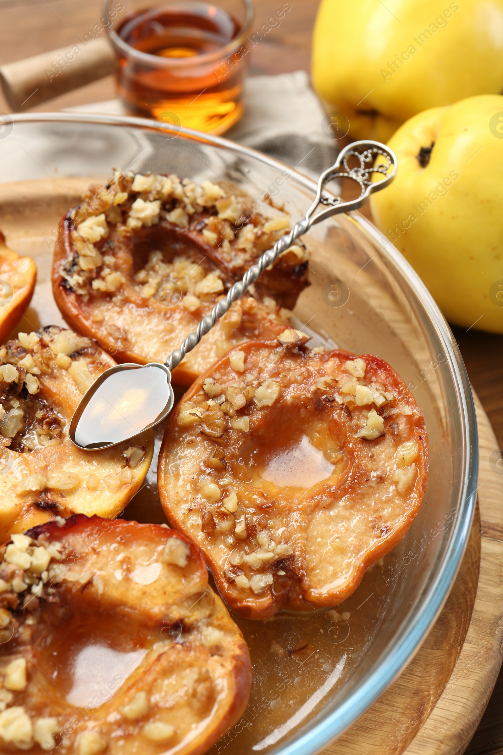 Photo of Tasty baked quinces with walnuts and honey in bowl on table, closeup