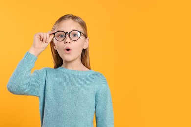 Photo of Portrait of emotional girl in glasses on orange background. Space for text