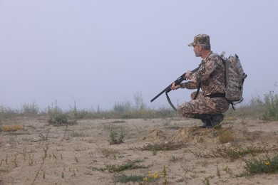 Photo of Man wearing camouflage with hunting rifle outdoors. Space for text