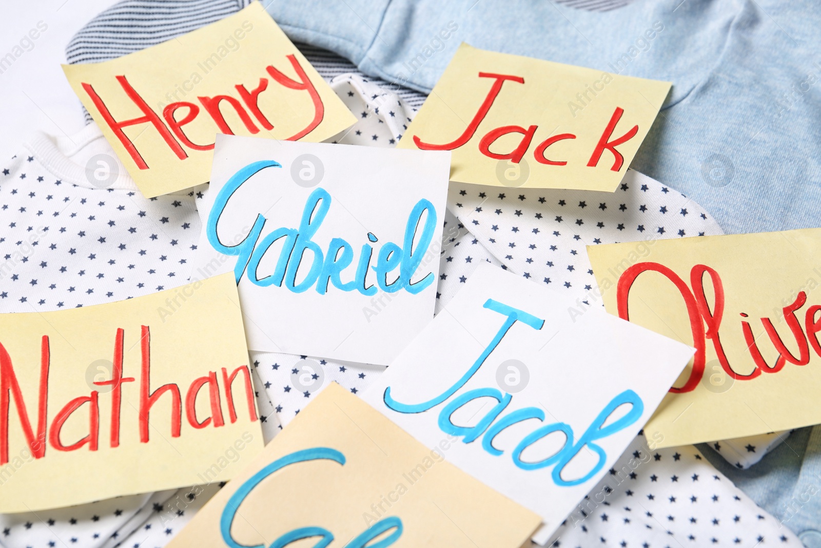 Photo of Many sticky notes with different baby names on child's clothes, closeup