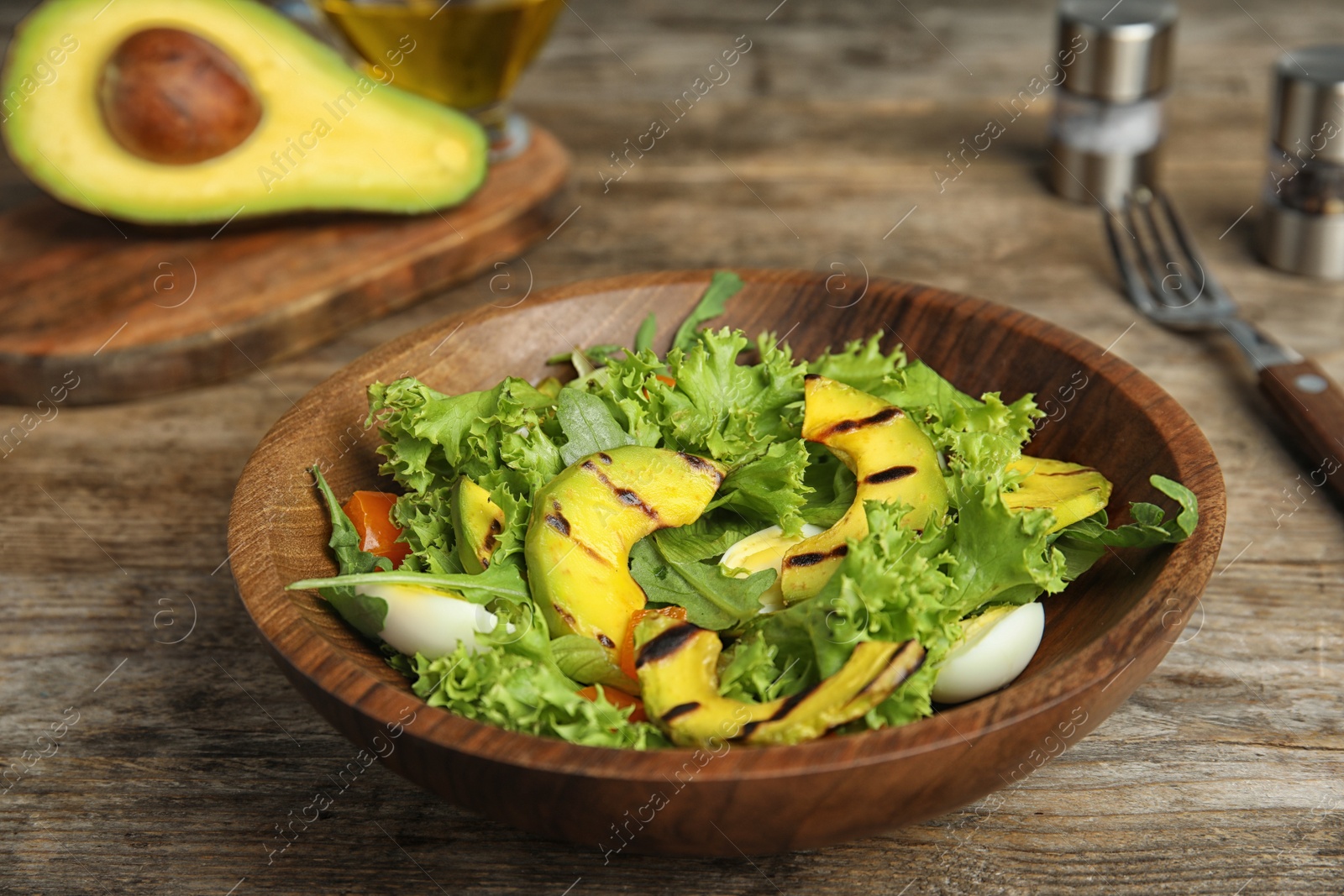 Photo of Delicious avocado salad with boiled eggs in bowl on wooden table