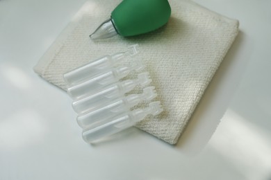 Single dose ampoules of sterile isotonic sea water solution, towel and nasal aspirator on white table