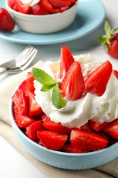 Photo of Delicious strawberries with whipped cream served on white table, closeup