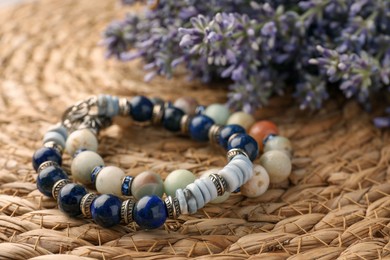 Beautiful bracelets with gemstones on wicker mat, closeup