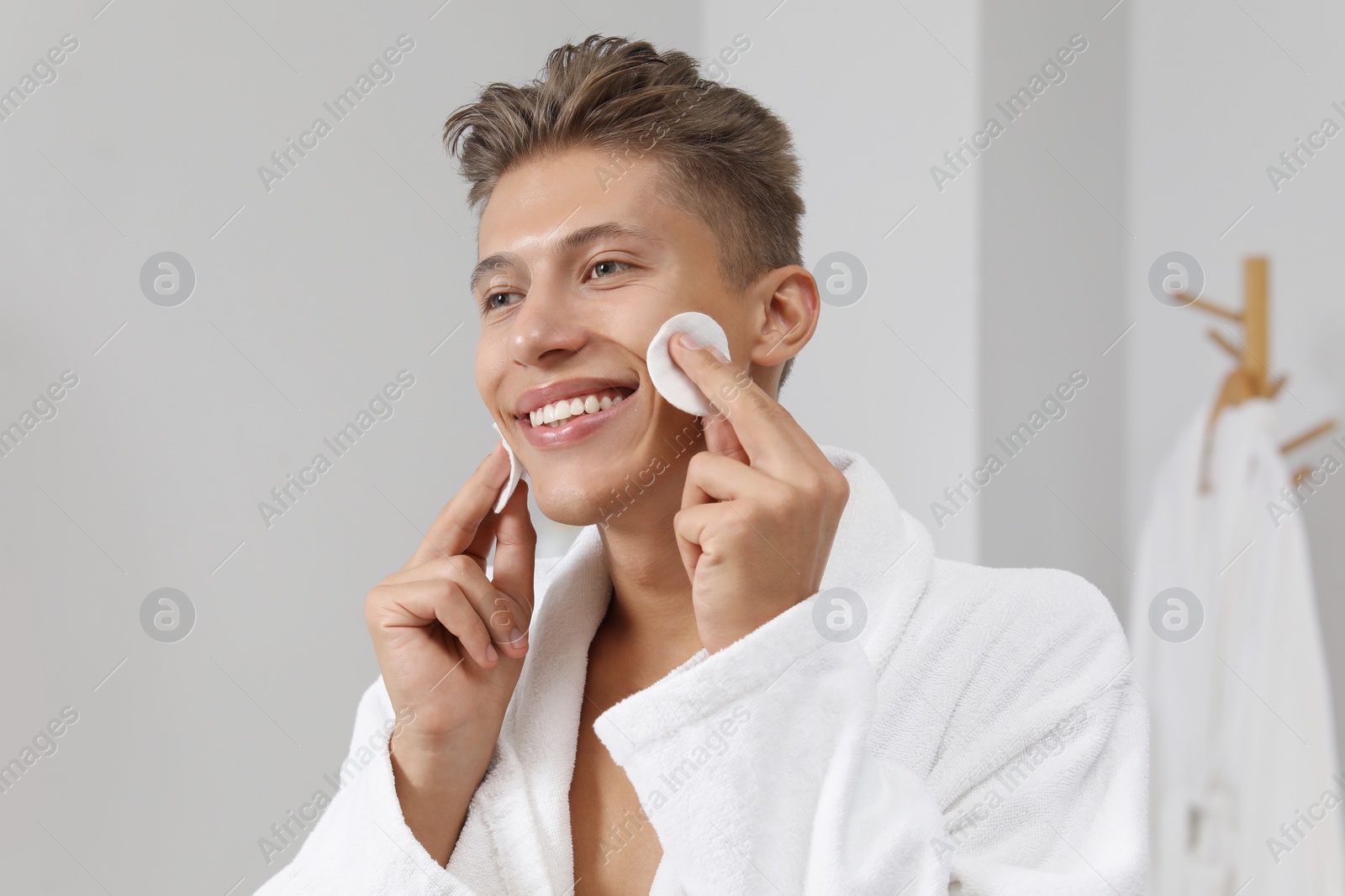 Photo of Handsome young man with cotton pads in bathroom