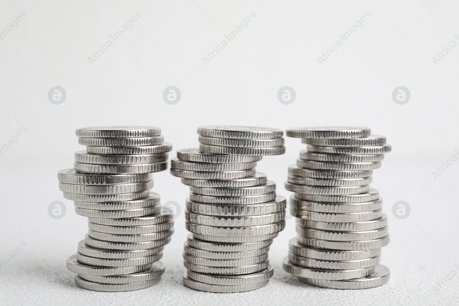 Photo of Many silver coins stacked on white table