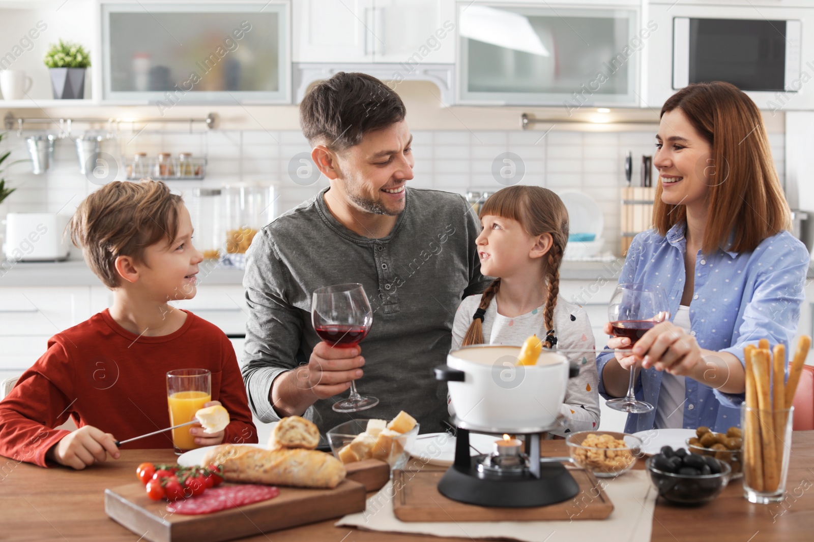 Photo of Happy family enjoying fondue dinner at home