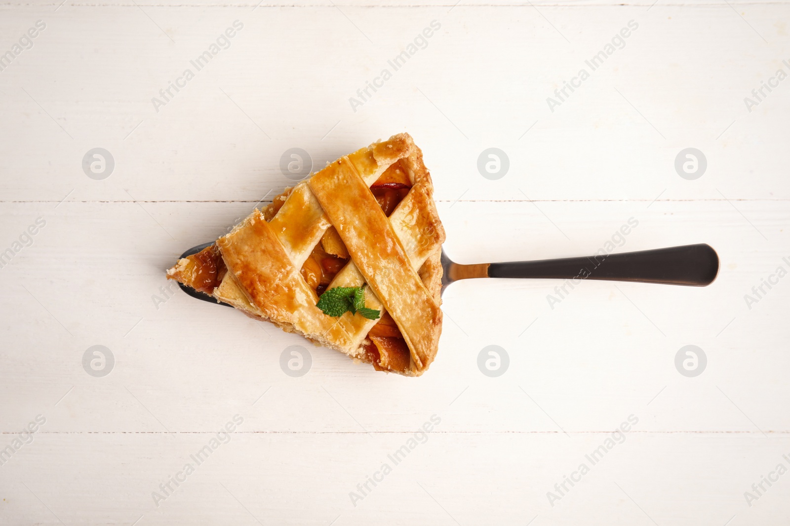 Photo of Slice of delicious fresh peach pie on white wooden table, top view