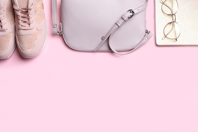 Stylish shoes, small woman's bag, notebook and glasses on pink background, flat lay. Space for text