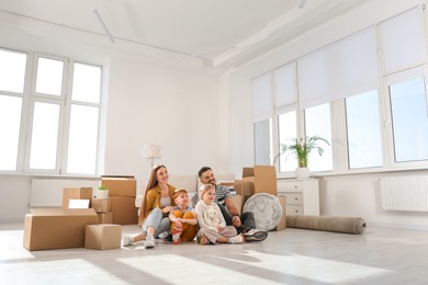 Photo of Happy family sitting on floor in new apartment. Moving day