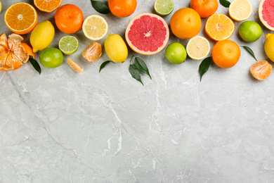 Flat lay composition with tangerines and different citrus fruits on grey marble background. Space for text