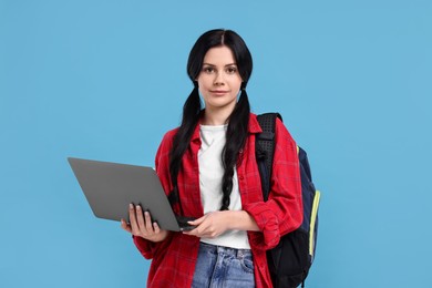 Student with laptop on light blue background