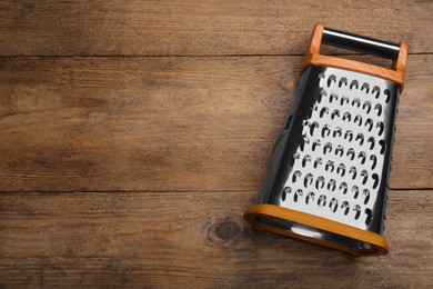 Modern grater on wooden table, top view. Space for text