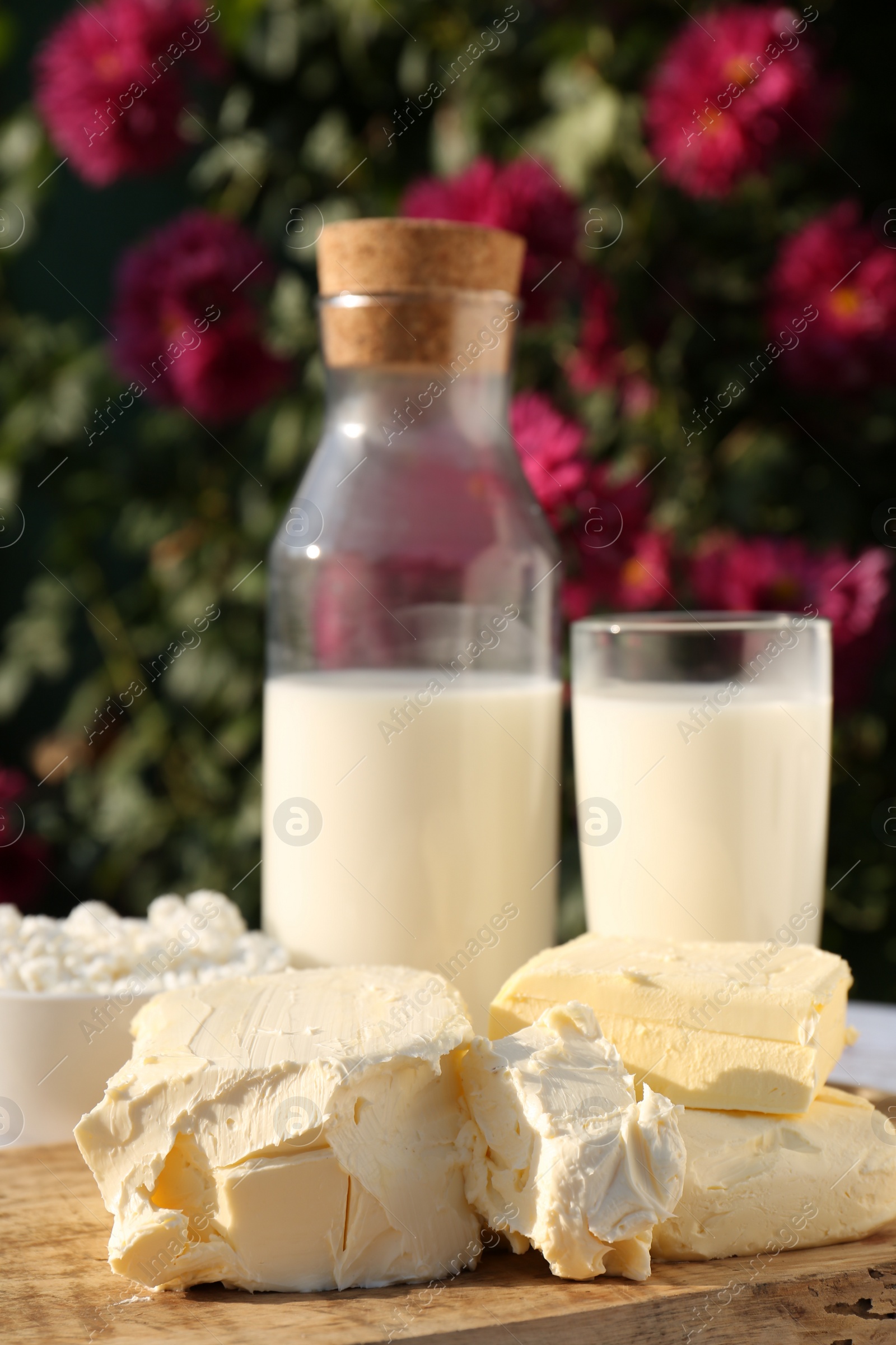 Photo of Tasty homemade butter and dairy products on white wooden table outdoors