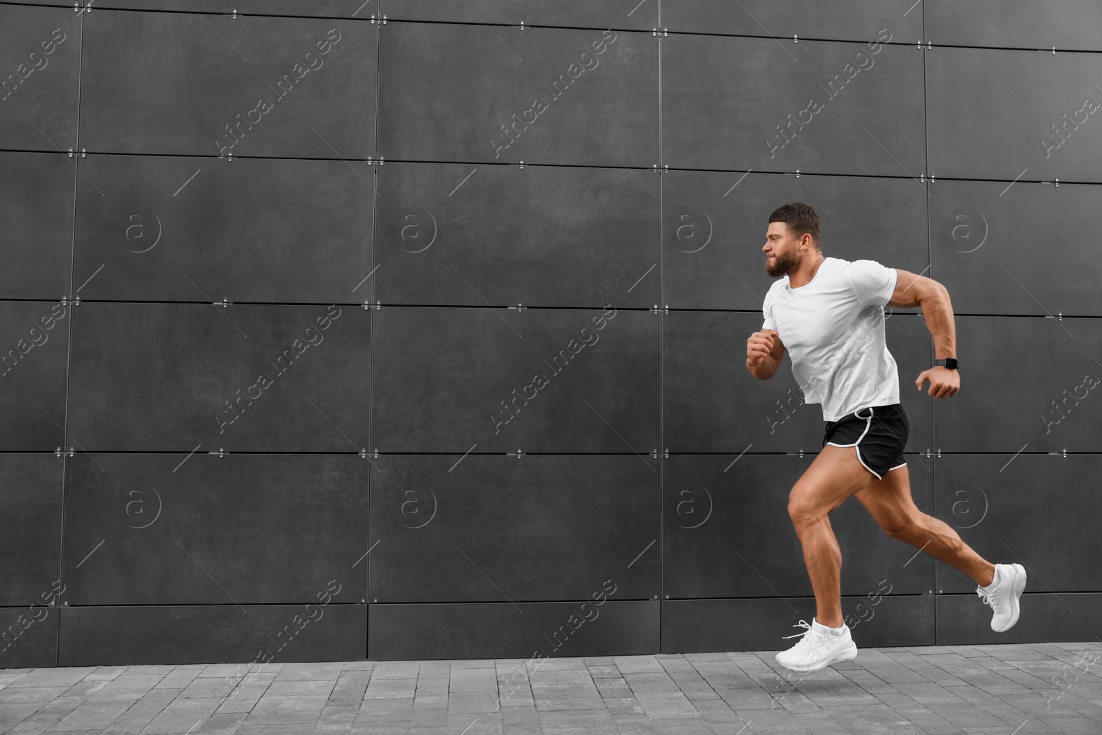 Photo of Young man running near building outdoors. Space for text