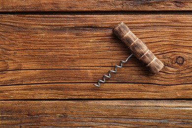 Photo of One corkscrew on wooden table, top view. Space for text