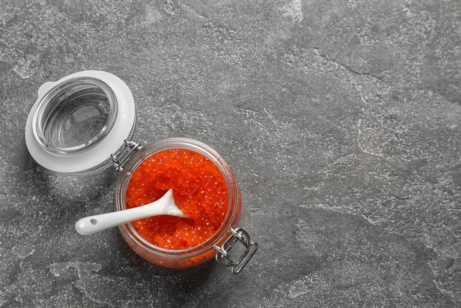 Photo of Jar with delicious red caviar on grey background