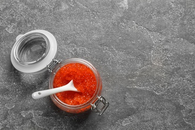 Jar with delicious red caviar on grey background