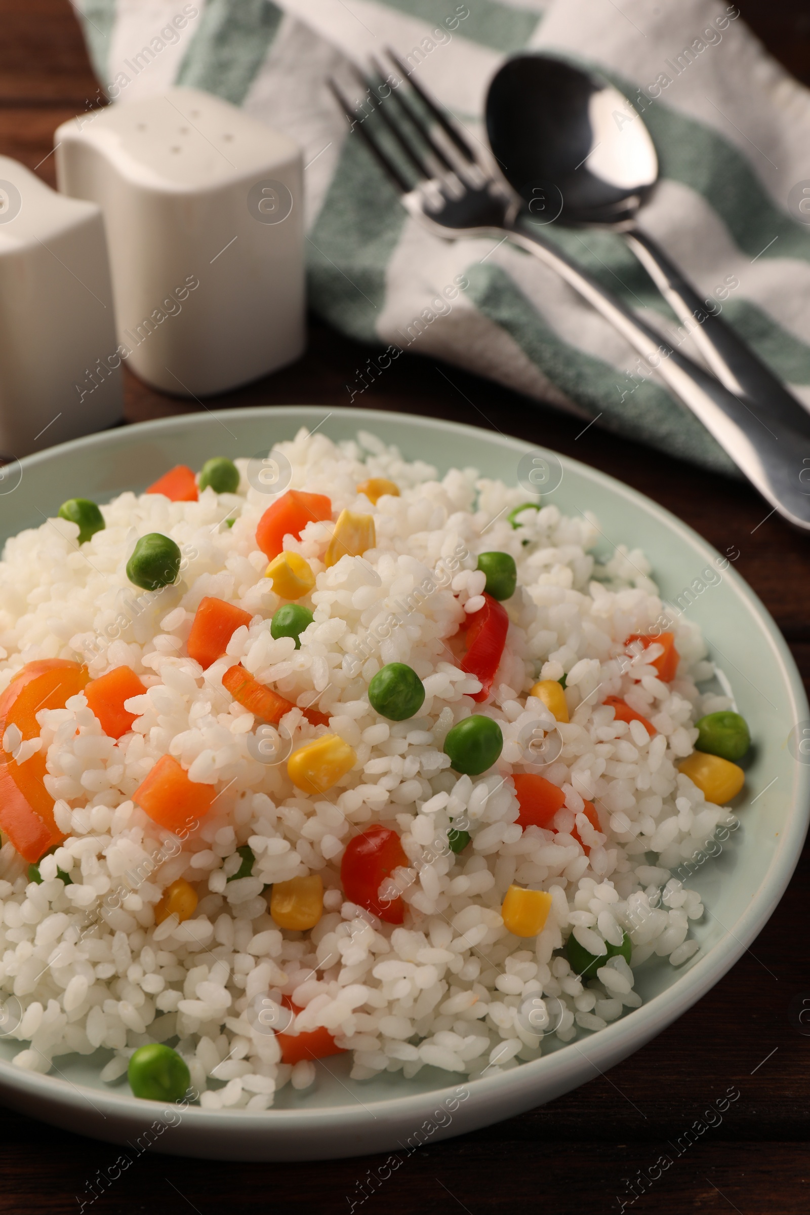 Photo of Delicious rice with vegetables on wooden table, closeup