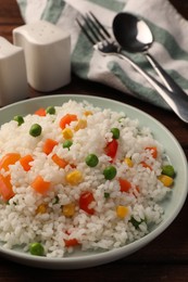 Delicious rice with vegetables on wooden table, closeup