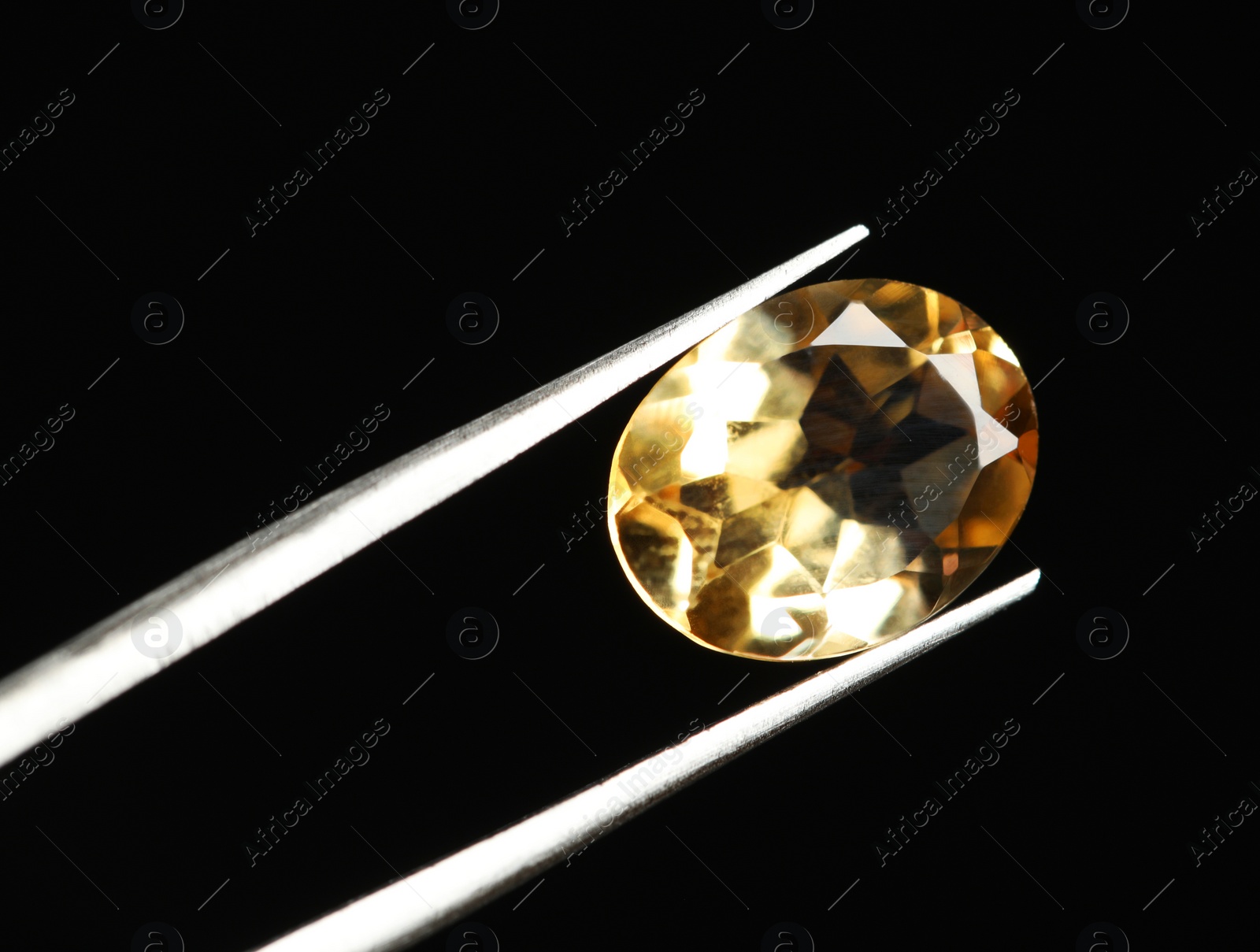 Photo of Tweezers with beautiful gemstone on black background