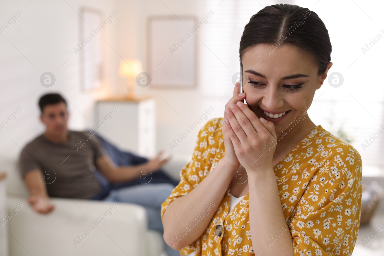 Photo of Woman preferring talking on phone over spending time with her boyfriend at home. Jealousy in relationship