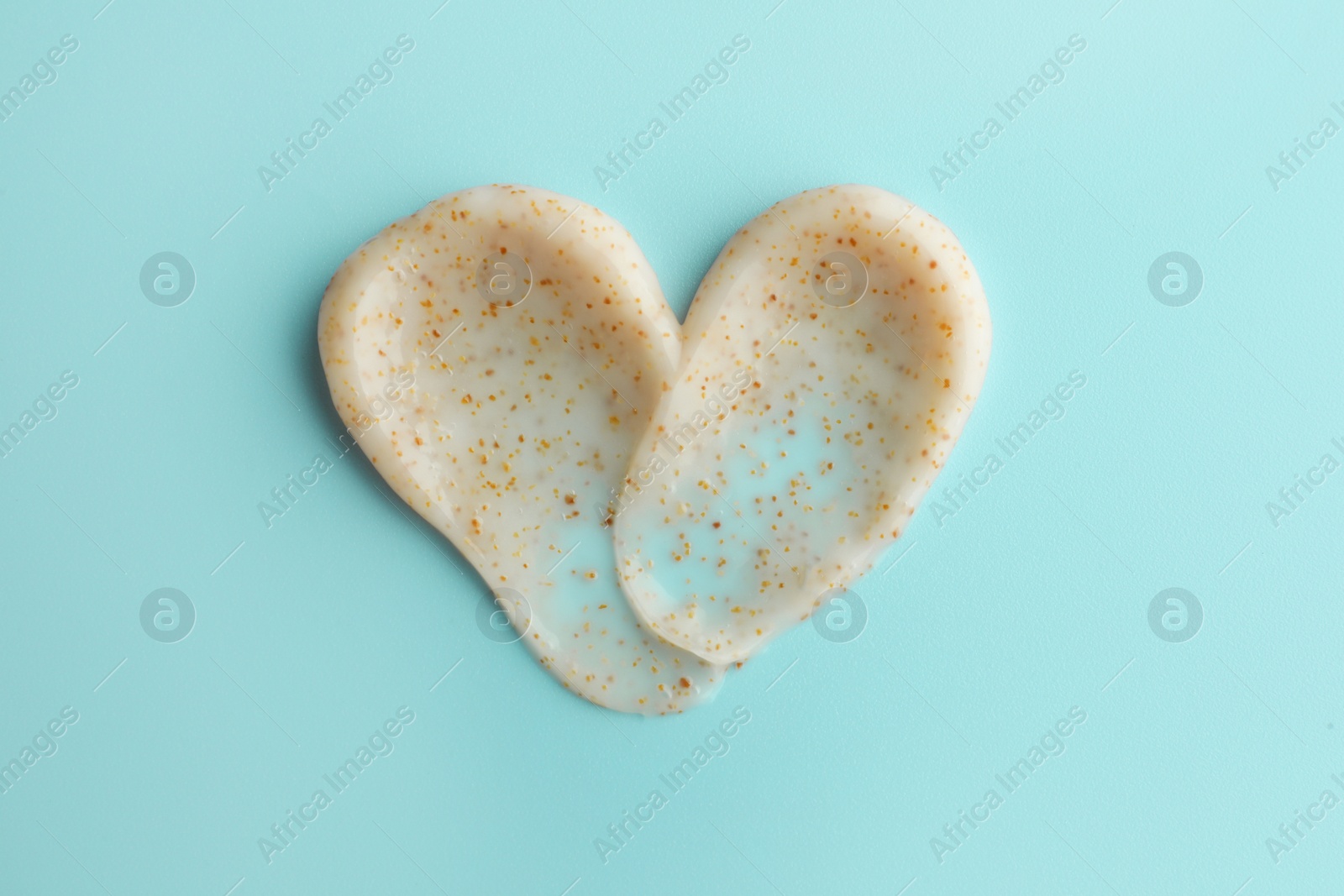 Photo of Samples of face scrub in shape of heart on light blue background, top view