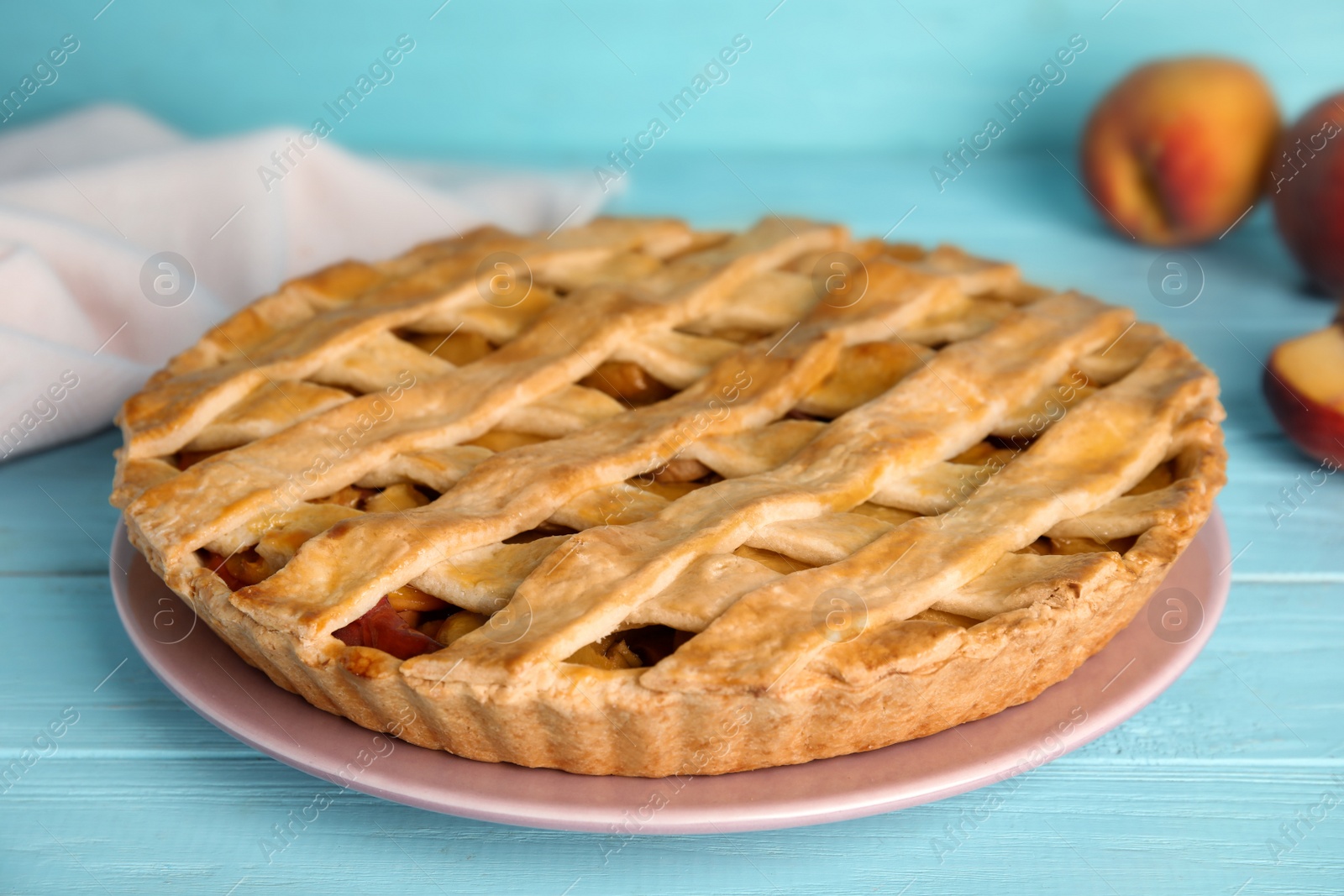 Photo of Delicious fresh peach pie on light blue wooden table, closeup