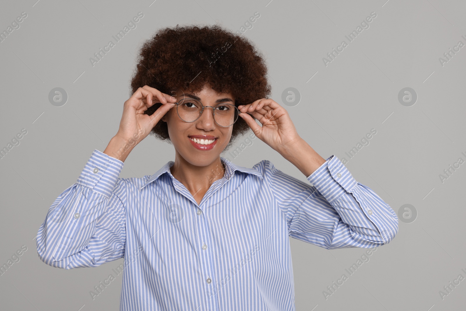 Photo of Portrait of happy young woman in eyeglasses on grey background