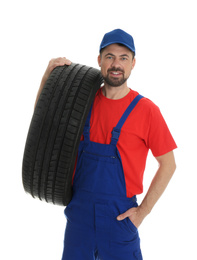 Portrait of professional auto mechanic with tire on white background