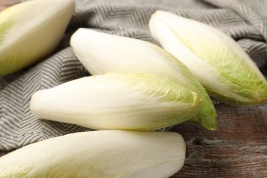 Photo of Fresh raw Belgian endives (chicory) on wooden table, closeup