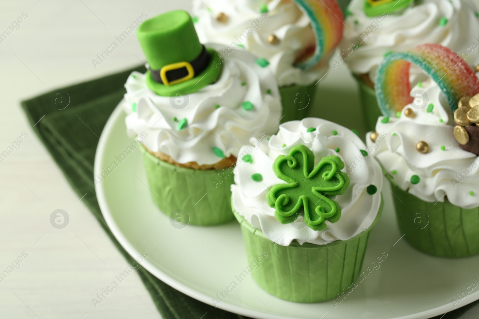 Photo of St. Patrick's day party. Tasty festively decorated cupcakes on white table, closeup