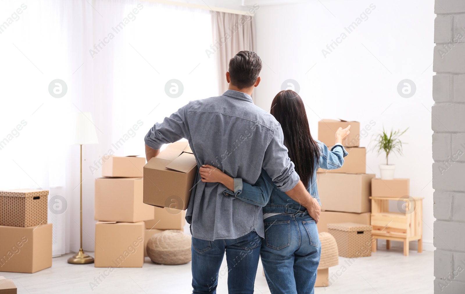 Photo of Couple in room with cardboard boxes on moving day