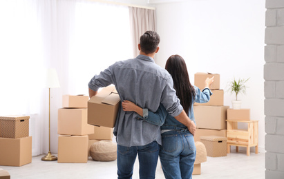 Couple in room with cardboard boxes on moving day