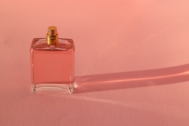 Photo of Luxury women's perfume in bottle on pale pink background. Space for text