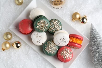 Beautifully decorated Christmas macarons and festive decor on snow, flat lay