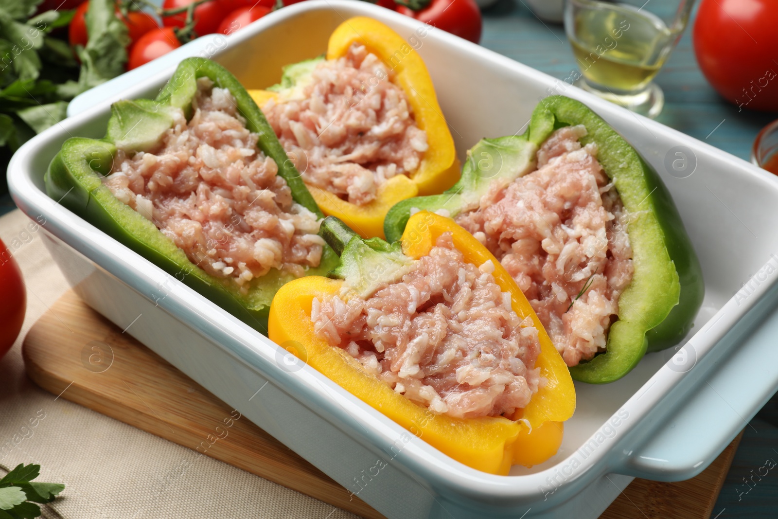 Photo of Raw stuffed peppers and ingredients on light blue wooden table, closeup