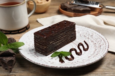 Piece of tasty chocolate cake and mint on wooden table